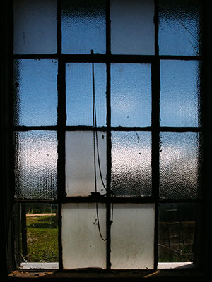 An old window with some panes frosted, some panes clear, and some panes broken.